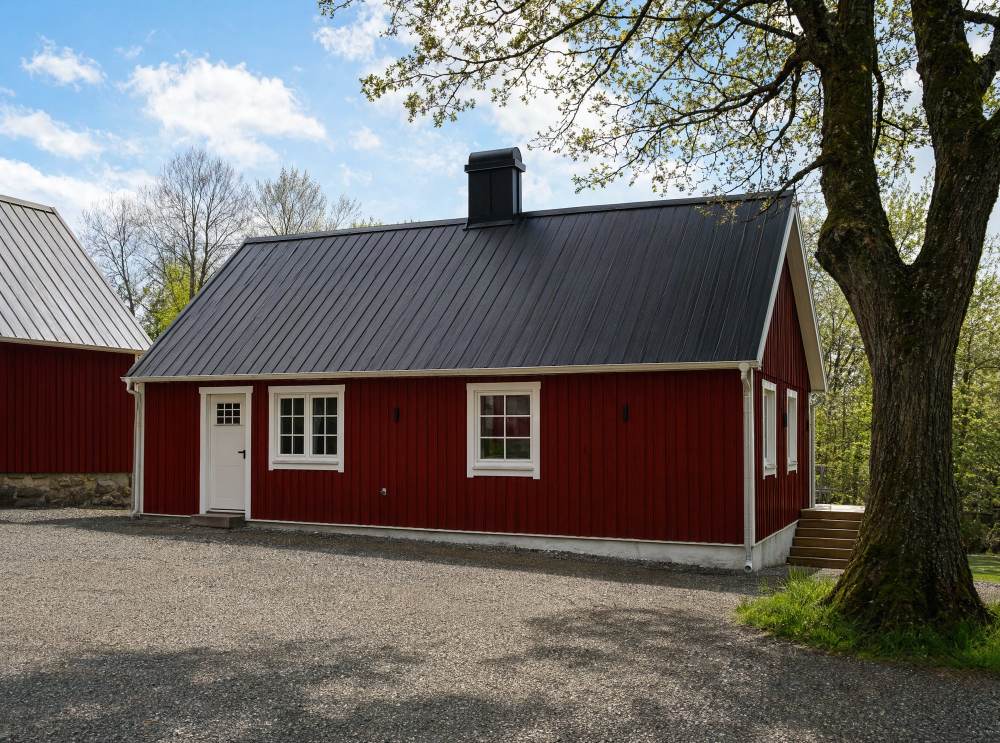 Rött trähus med vita knutar och stor trätrall