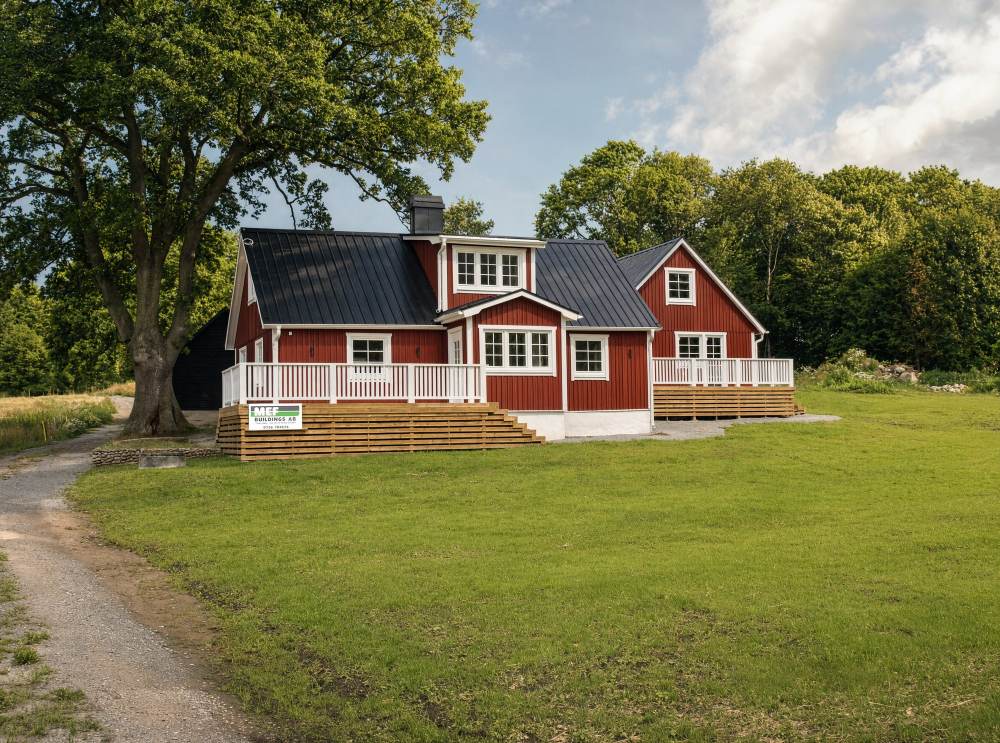 Rött trähus med vit veranda och svart plåttak