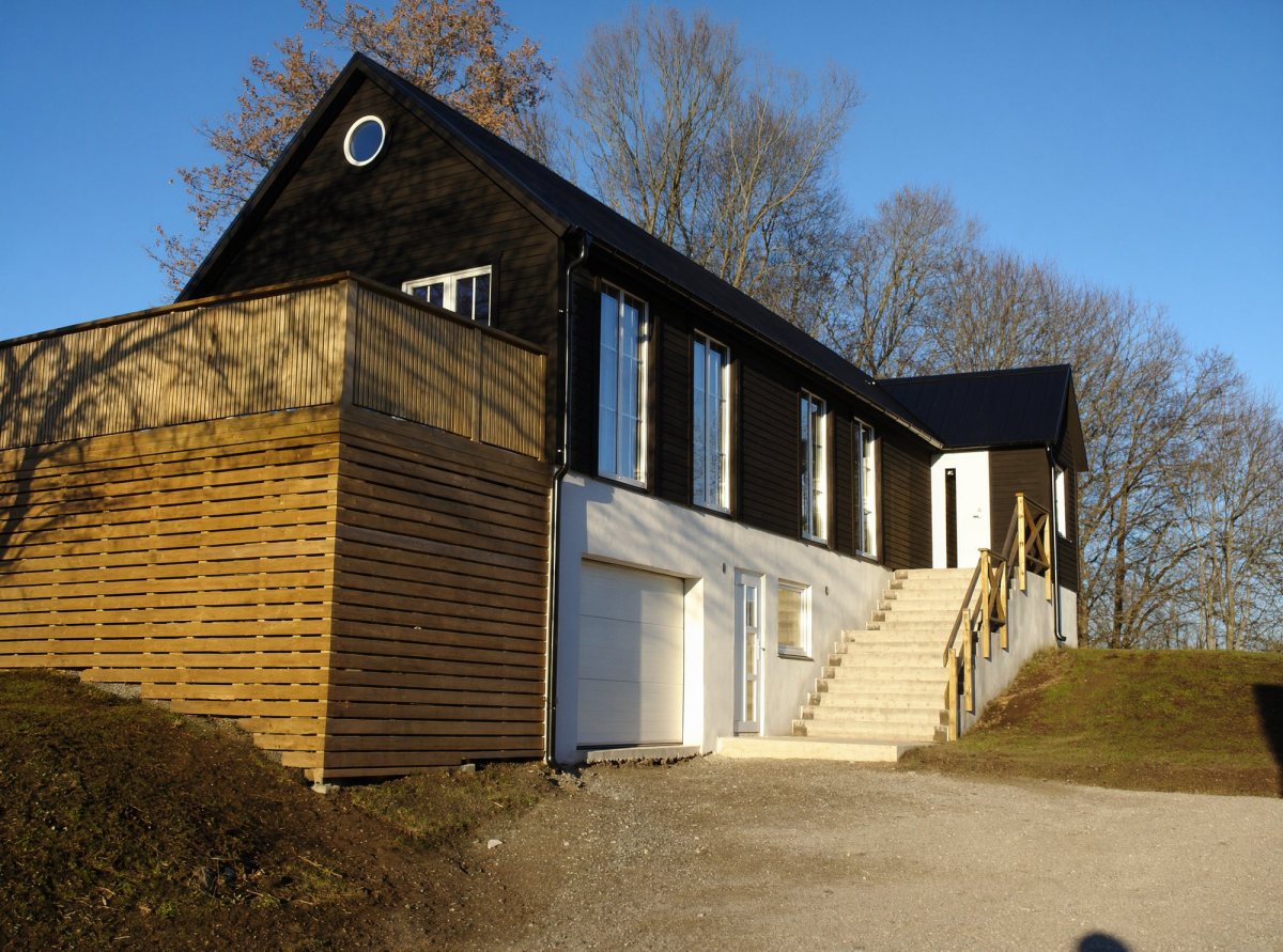 Nybyggt svart hus med träbeklädd terrass och stor trappa